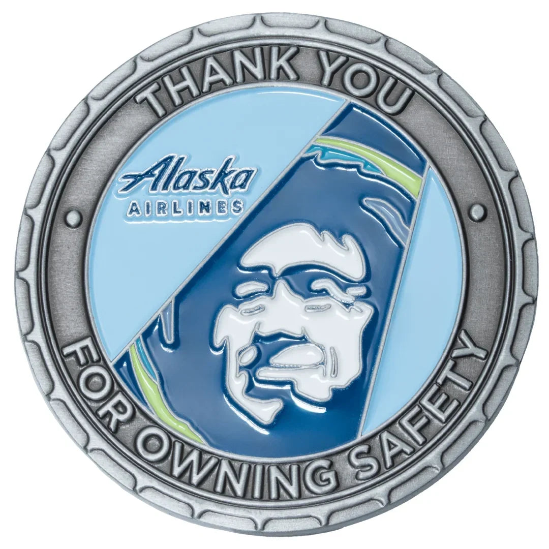 Round silver medallion with blue enamel, showing a corporate logo and a stylised portrait face