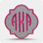 Custom embroidered monogram patch stitched in pink thread on a metallic silver background